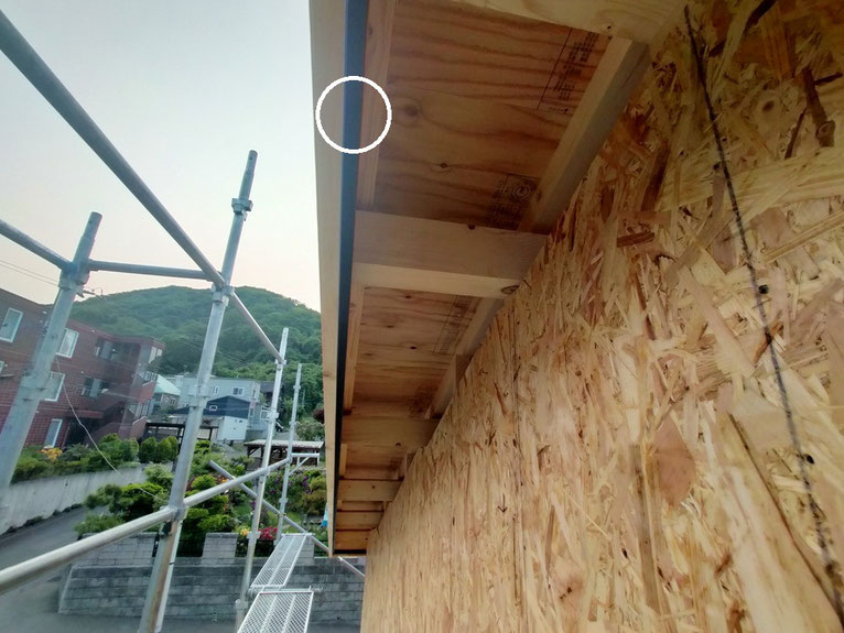 屋根の軒先部分を下から見上げた写真。換気用の細長い開口部が見える。
