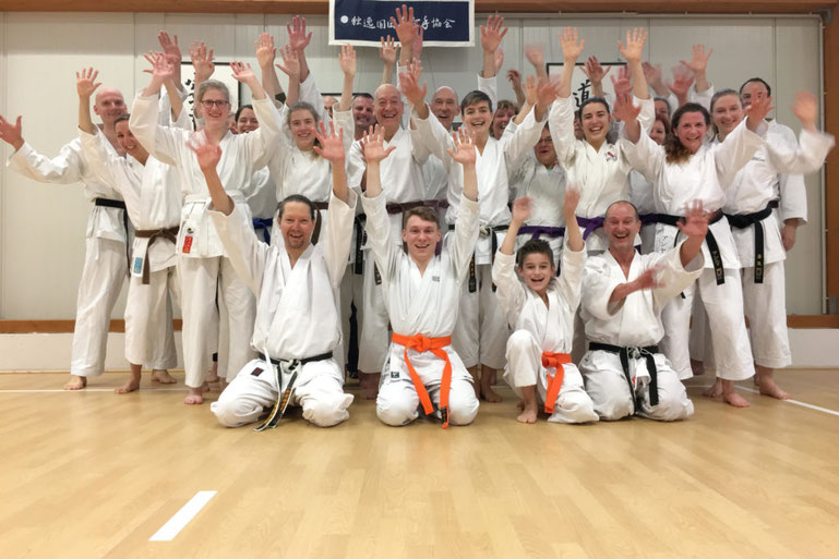 Karate-Schüler machen ein Gruppenfoto und freuen sich über bestandene Prüfungen.