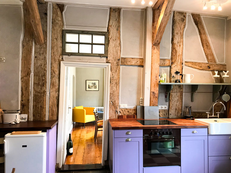 Die Küche der Ferienwohnung mit Blick in das Wohnzimmer. Im Fokus steht das alte Fachwerk.