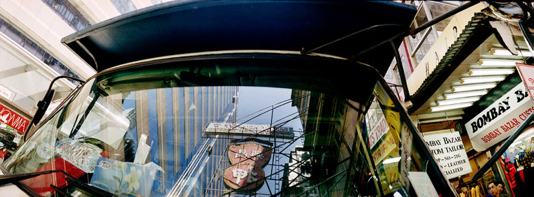 Spiegelung des Straßenlebens in Hongkong, China, als Farbphoto im Panorama-Format