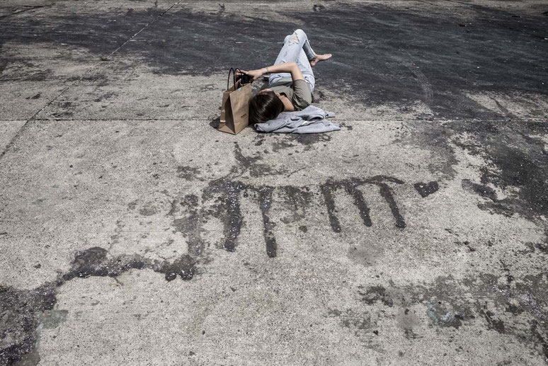 Junge Frau liegt auf einer Betonfläche am Yuigahama Beach in Kamakura, Japan als Farbphoto