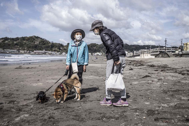 Zwei ältere Frauen mit Hund unterhalten sich auf demYuigahama Beach in Kamakura, Japan als Farbphoto