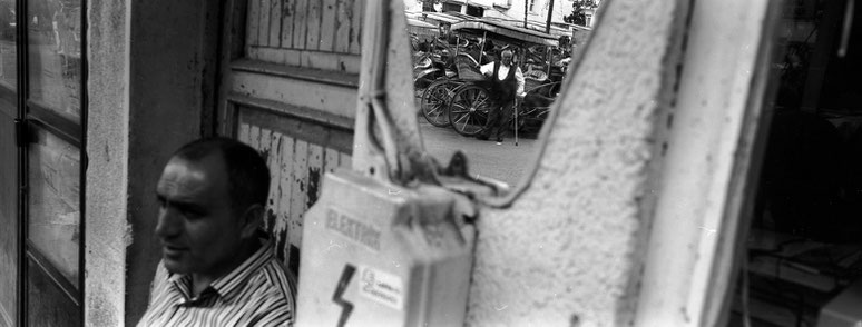 Spiegelung eines Kutschers auf der Büyükada Prinzesininsel in Istanbul, Türkei als Schwarzweißphoto im Panorama-Format