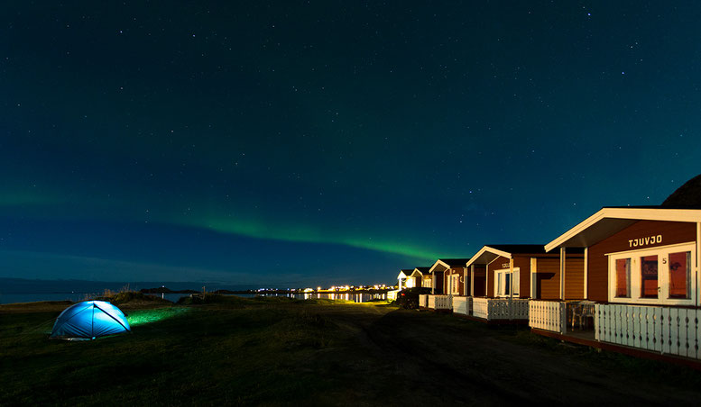 Illuminated tent and wooden cabins at Ramberg beach, Lofoten Islands, Norway, Scandinavia, Europe
