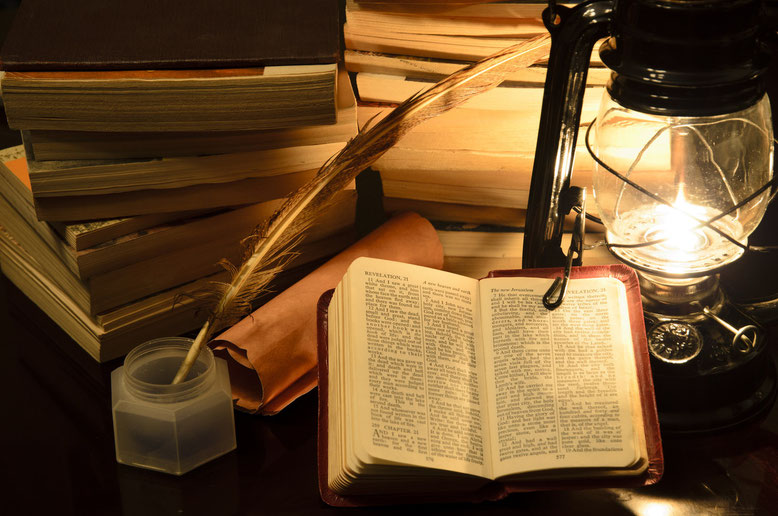 Bücherstapel, Tintenfass mit Feder, offene Bibel und Laterne mit Kerze