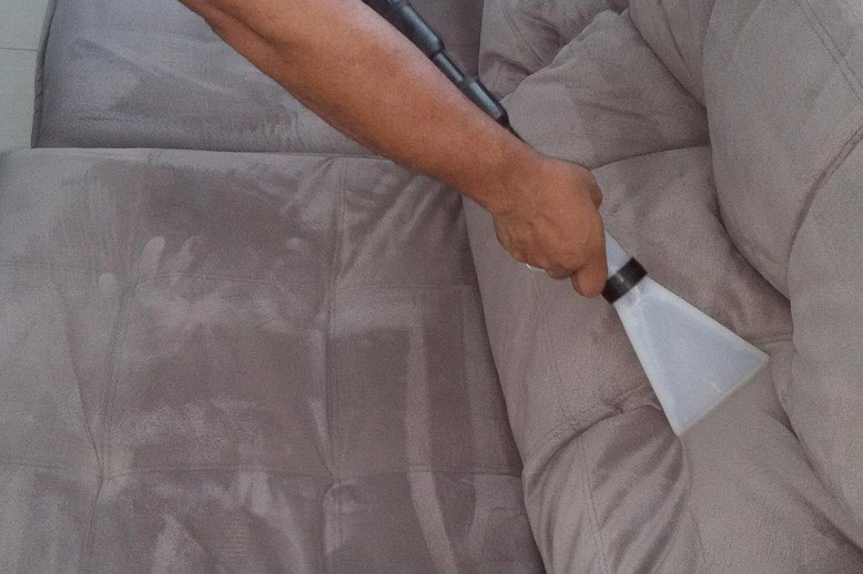 Person, die ein Sofa reinigt