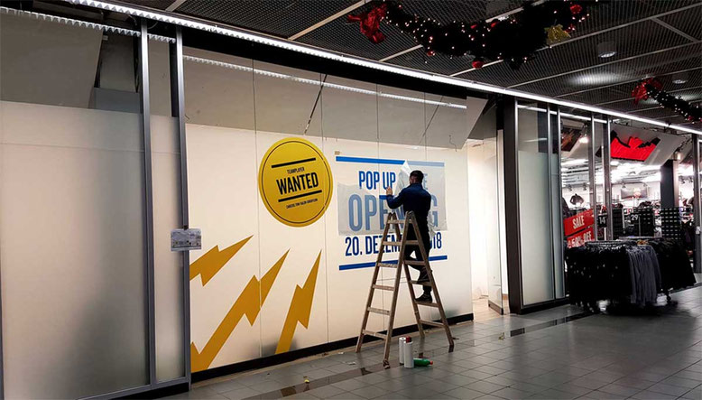 Montage eines Großformatdrucks zur Ankündigung einer Neueröffnung