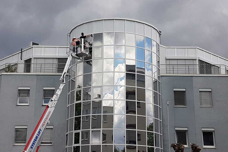 Montage von Sonnenschutzfolie an einer großen Glasfassade mit Hubsteiger