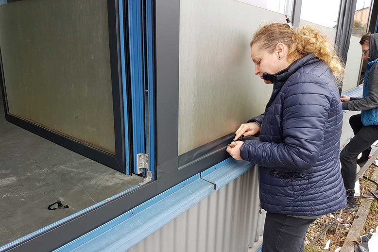 Detailarbeit bei der Montage von Folie für Fensterrahmen an einem Gebäude