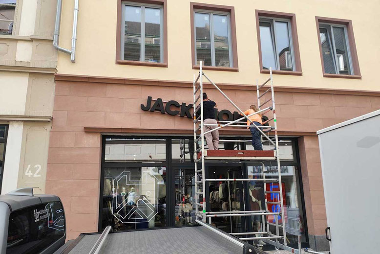 Montage einer Außenbeschilderung an einem Modegeschäft durch Werbetechniker