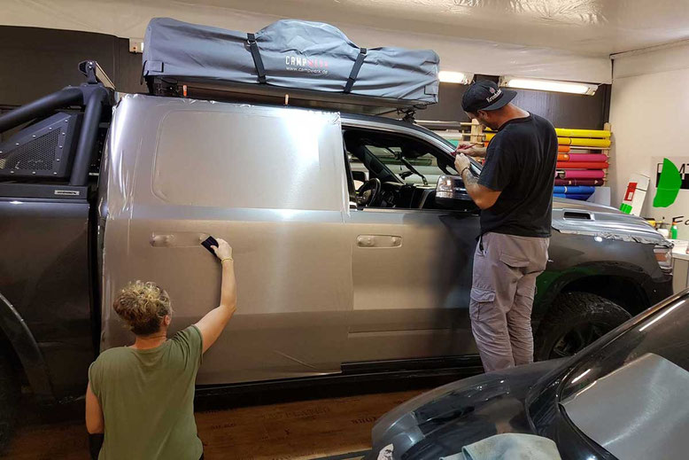 Folierung eines Offroad-Fahrzeugs in der Werkstatt durch zwei Folientechniker