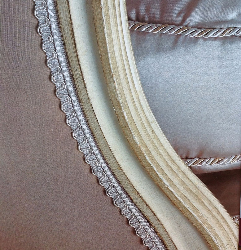 Passementerie lézarde, galon dentelé en tissu, grise, orne le pourtour d'une bergère Louis XVI en satin gris. Photo fournisseur.