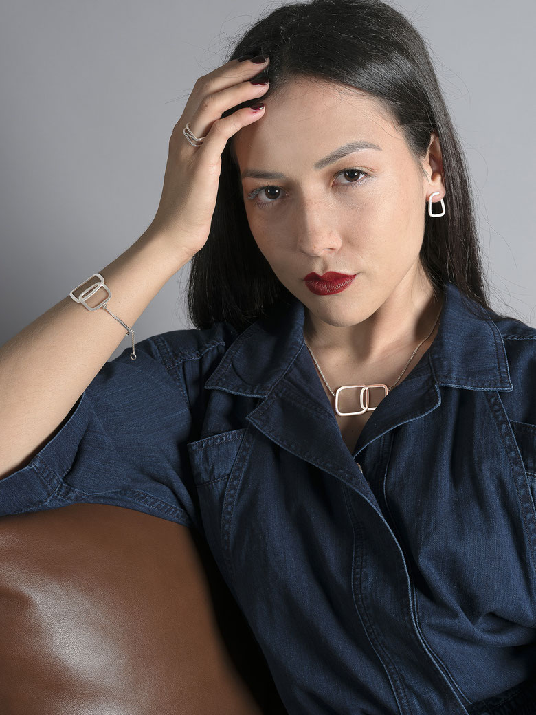 jeune femme accoudée qui porte un collier, un bracelet, une bague et des boucles d'oreilles en argent recyclé de la collection Quadra