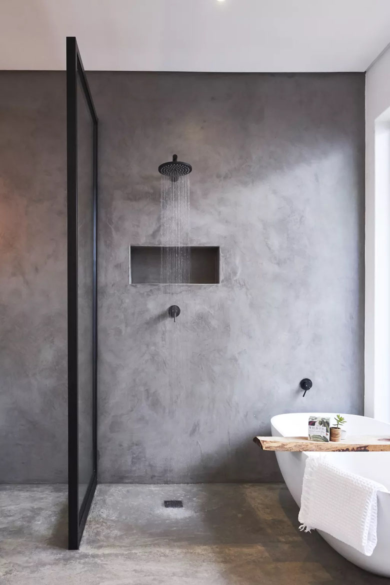 Luxury matt black rain shower next to a white freestanding bathtub with a large single panel framed shower screen