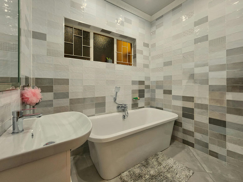 This is a modern bathroom with a freestanding bathtub, neutral-toned wall tiles, and a sleek sink, creating a clean and calming atmosphere.