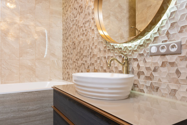 Bathroom renovation with sink on cabinet near bath with all gold fittings