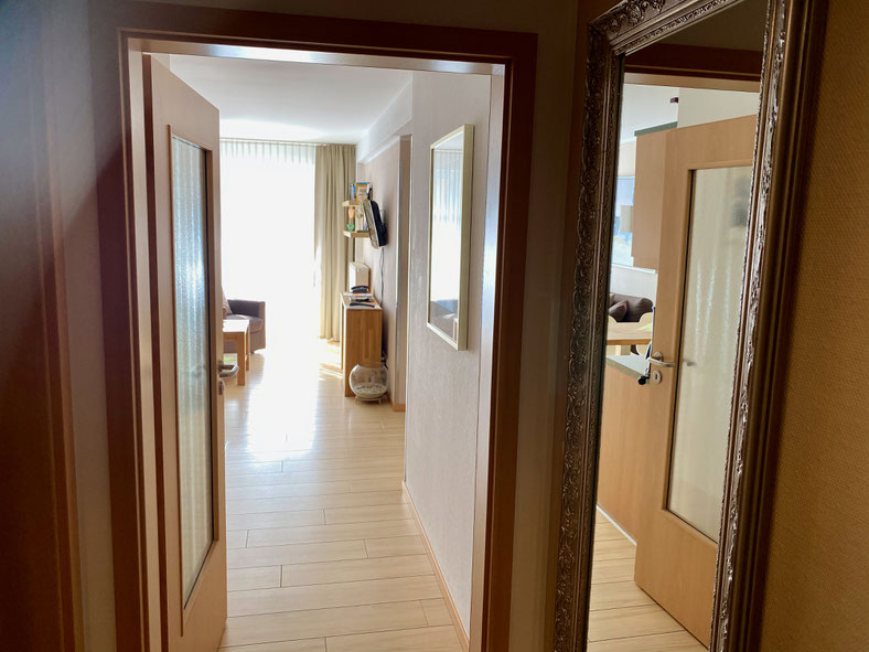 Vom Eingang geht es über den Flur mit viel Stauraum links ins Bad und geradeaus ins offene Wohnzimmer mit großem Balkon.