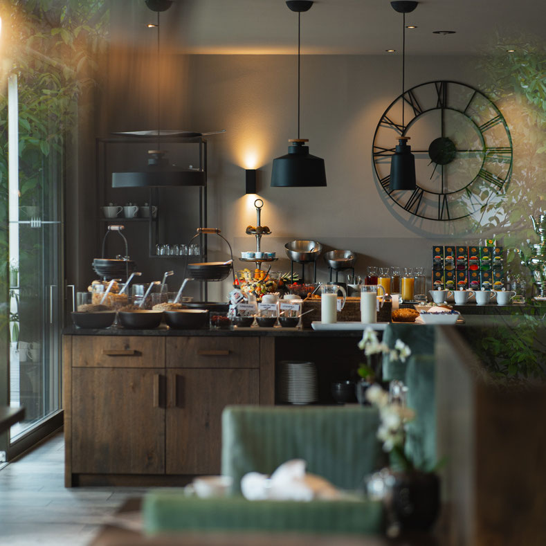 Modernes Frühstücksbuffet mit regionalen Speisen, frischem Obst, Säften und Heißgetränken im stilvoll gestalteten Speiseraum des Hotel Mair am Ort Living in Partschins bei Meran in Südtirol.