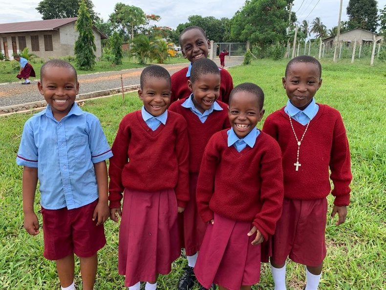 Eine Gruppe afrikanischer Kinder in Schulkleidung lacht in die Kamera.