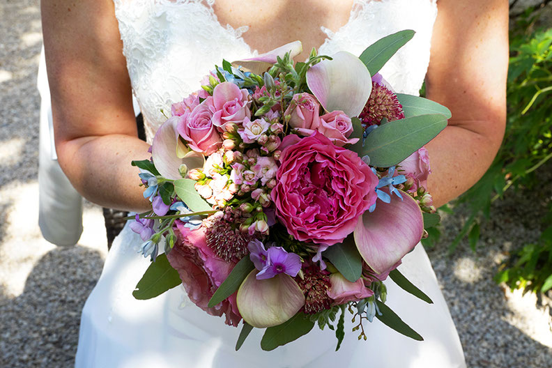Photographie couleur, gros plan d'un bouquet de fleurs roses, violettes. dans la main dune jeune mariée dont on ne voit pas le visage. Genève. 