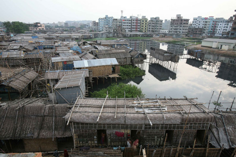 High rise buildings tower over the makeshift houses in this slum. Dhaka, Bangladesh,