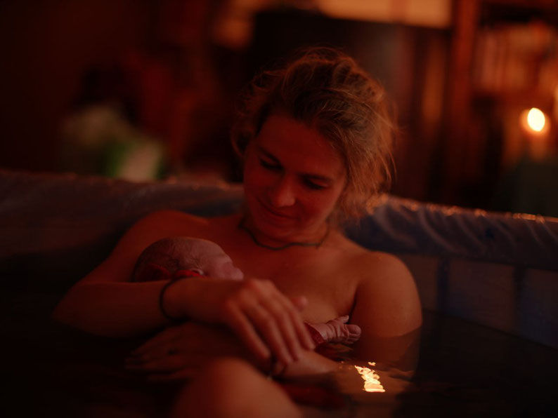 Eine Frau, Alia Ciobanu, nach der Wassergeburt glücklich mit ihrem Baby im Gebärpool. 