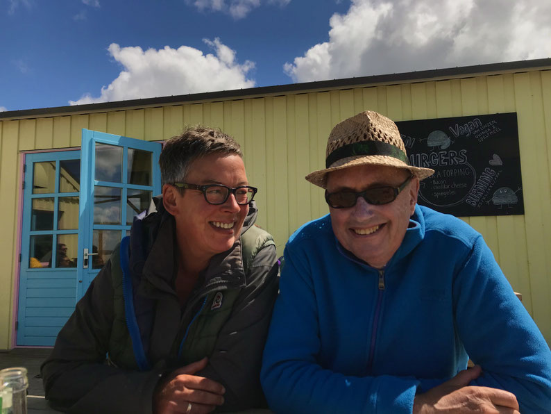 Eine Frau und ein Mann sitzen vor einem Café in der Sonne