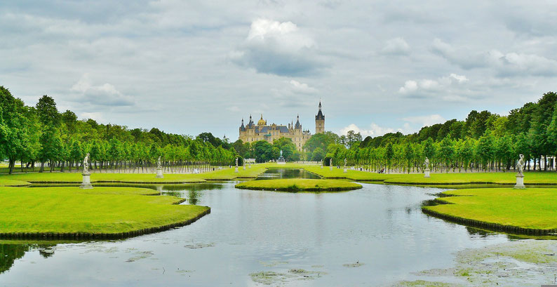 Ein Schloss mit vielen Türmen in einem Park mit Wasserflächen
