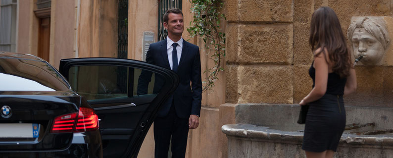 Chauffeur ouvrant la portière à ses clients pour faciliter leur embarquement à bord de la berline