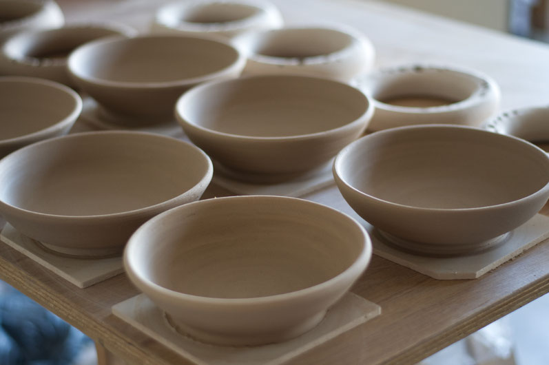 Freshly trown handmade ceramic bowls on a table, waiting to dry, ready for further processing