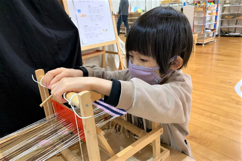 京都市の幼児教室バンビー二クレアーレ。モンテッソーリの個別活動で幼稚園児が機織りの活動をしています。