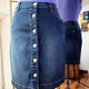 Sur l'image, une jupe en jean droite avec des boutons tout le long du devant.