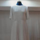 Sur l'image, une robe à manches courtes en lin blanc. Coupée à la taille, la jupe longue part en un léger évasée. Réalisation sur commande de la maison de couture Fil et Paillettes.