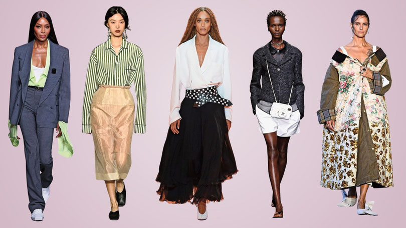 Fünf diverse Models, darunter Naomi Campbell, präsentieren auf einem Laufsteg verschiedene Designermode-Outfits, von Hosenanzügen über Röcke bis hin zu Statement-Mänteln, vor einem rosa Hintergrund