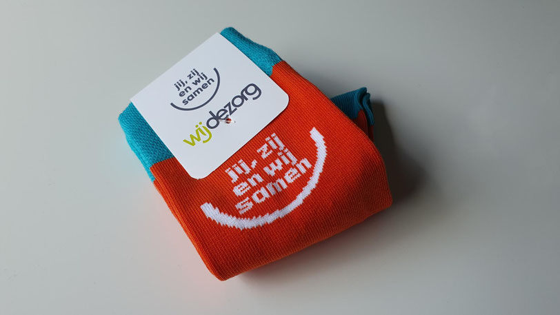 Zorgpersoneel in uniform draagt gepersonaliseerde zorgsokken met logo en medische symbolen