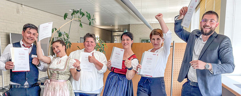 Absolvent:innen jubeln mit Urkunde in der Hand