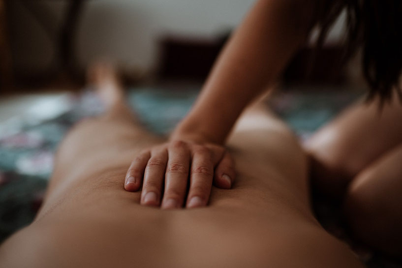 Eine Nahaufnahme, die zeigt, wie die Hand einer Person während einer Massage Druck auf den unteren Rücken eines Kunden ausübt.