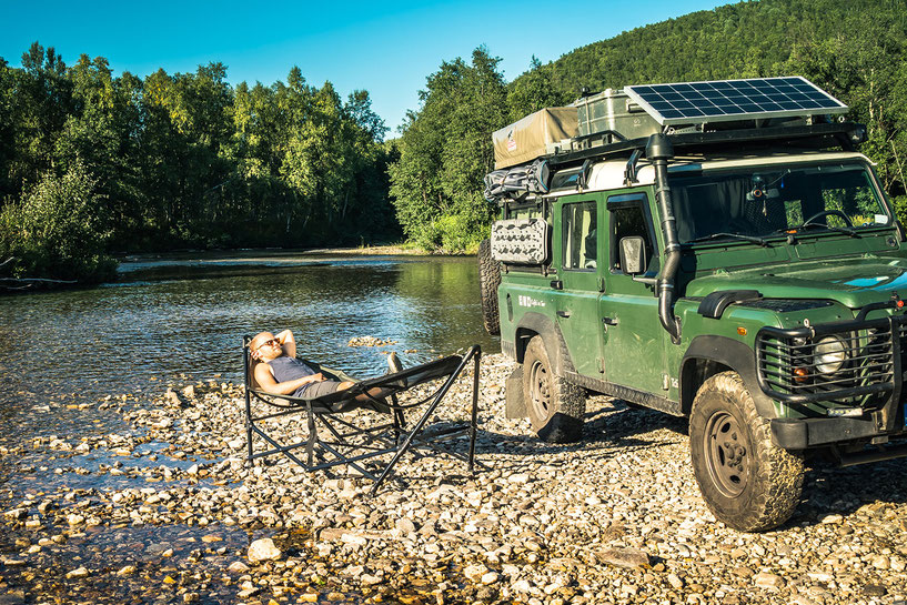 Relaxing in the Tembo hammock near a river with the Land Rover Defender