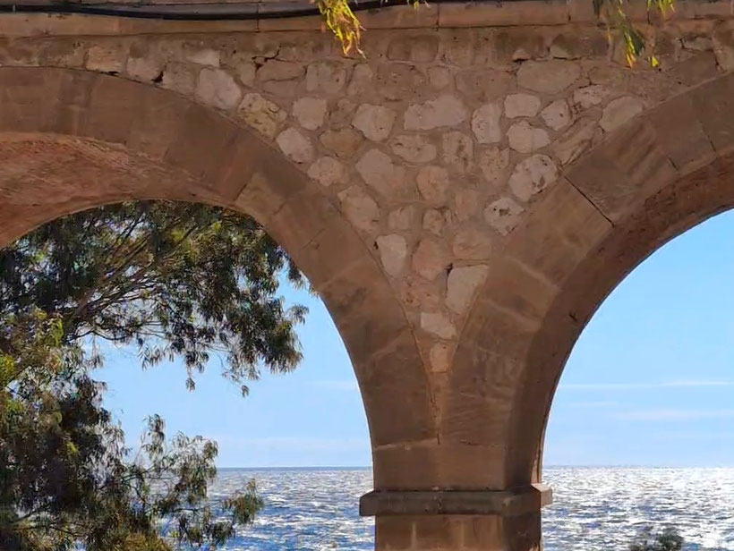 durch die zwei Bögen eines Viaductes sieht man das blaue Meer und den blauen Himmel