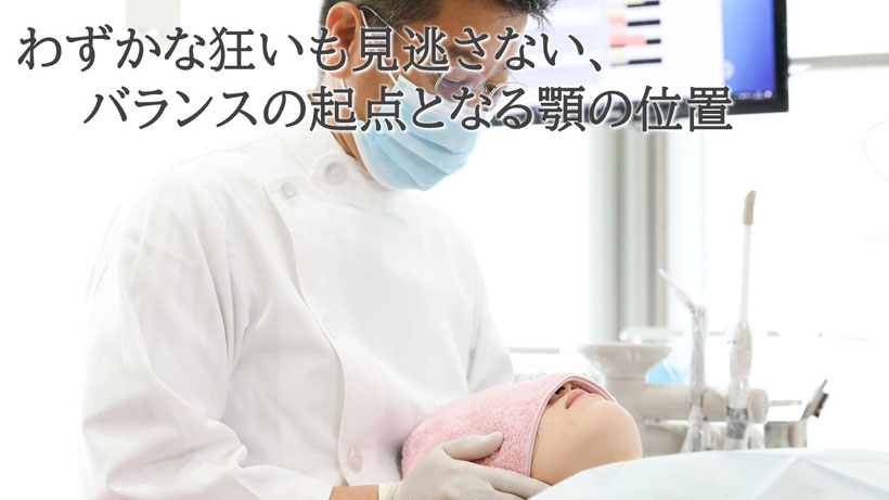 顎の位置を手の感覚で探している歯科医師の写真