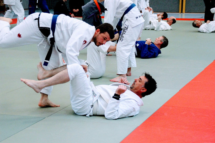 Brazilian Jiu Jitsu Bodenkampf -ein Partner verteidigt sich durch die Guardposition (Abwehrhaltung mit den Beinen) gegen die Angriffe des anderen Kämpfers, der diese Verteidigungsposition zunächst erst einmal passieren muss