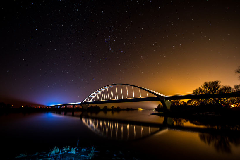 Die Schönheit einer mondlosen Nacht,eingefangen an der Elbebrücke Tangermünde. Rechts zeigen sich die Lichter der Stadt im Bild,links ziehen die Autos ihre Lichtstreifen über der Brücke.In der Mitte thront das Wintersternbild Orion am Himmel.