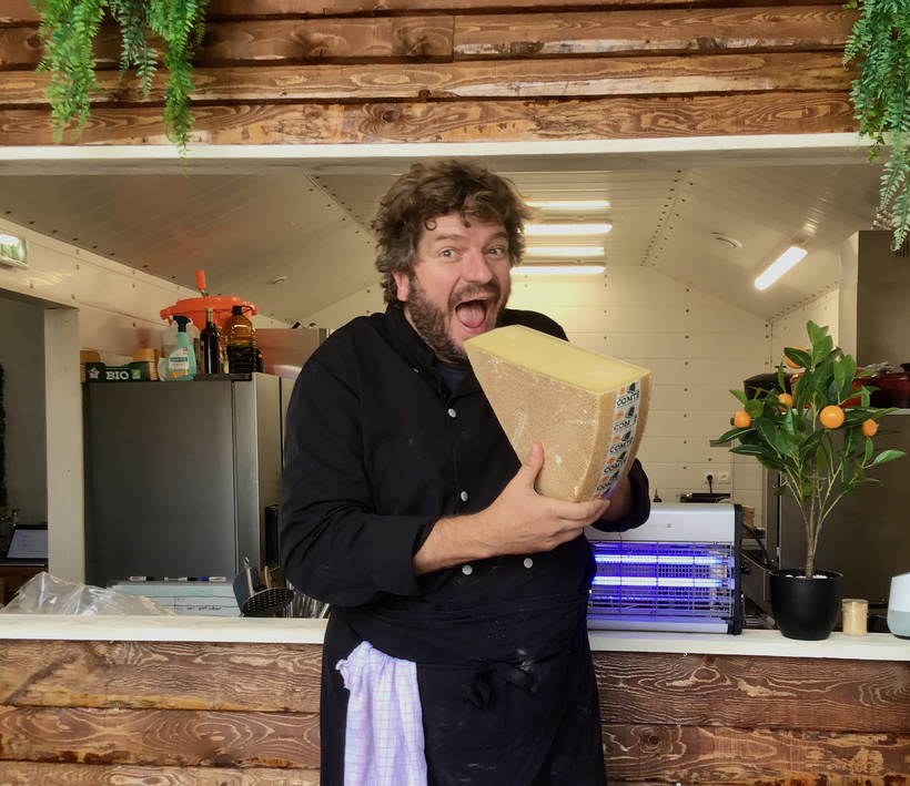 Walter de Mehlknepfle tient dans ses mains une pointe de Comté, il utilise ce délicieux fromage sur plusieurs de ses pizzas.