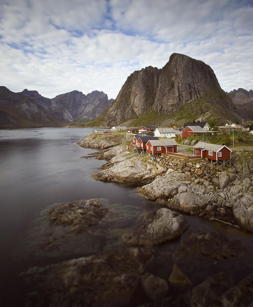 Red Fishermen houses in beautiful landscape with ocean, mountains, tilt shift exposure, Lofoten Islands, Norway, 1280x1547px