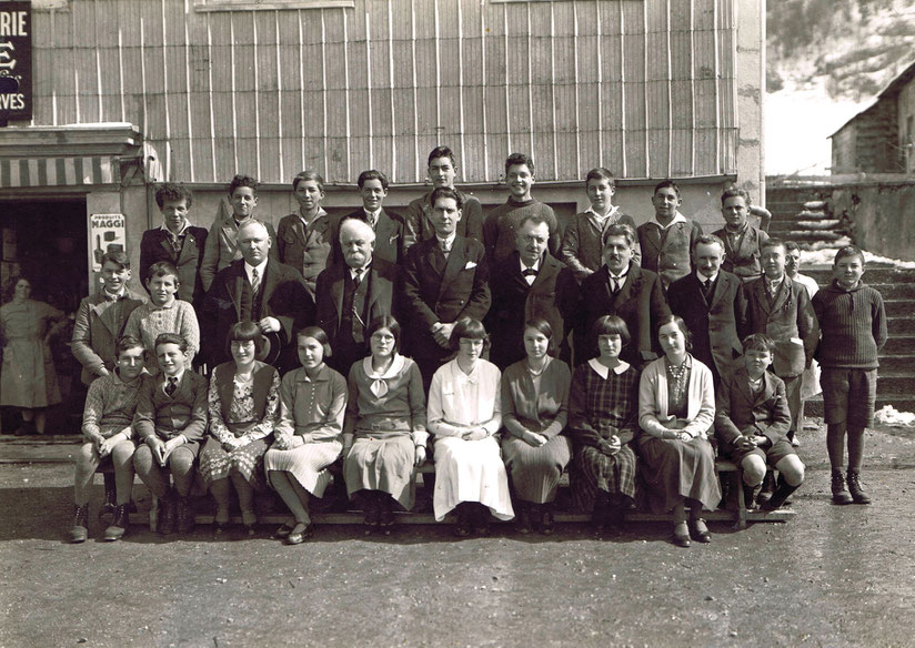 Gli alunni della prima superiore di Le Pont, 1932. L'istitutore George Muller si trova giusto al centro, circondato dai Membri della Commissione, dall'aria severa. Sullo sfondo, la scuola e la panetteria