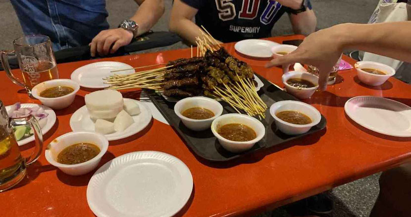 Satay street in Singapore - people eating local satay 