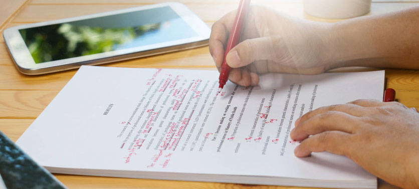 A hand with a pen making corrections in a text