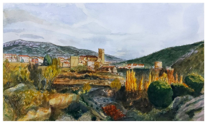 Pueblo de Priego con casas de tejados rojizos, torre de iglesia y colinas arboladas bajo cielo nublado.