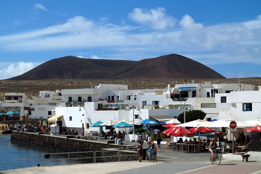 Abschied von La Graciosa. Blick vom Schiff zurück auf Caleta del Sebo. Im Hintergrund der Vulkan Montaña del Mojon mit 188 Metern Höhe.