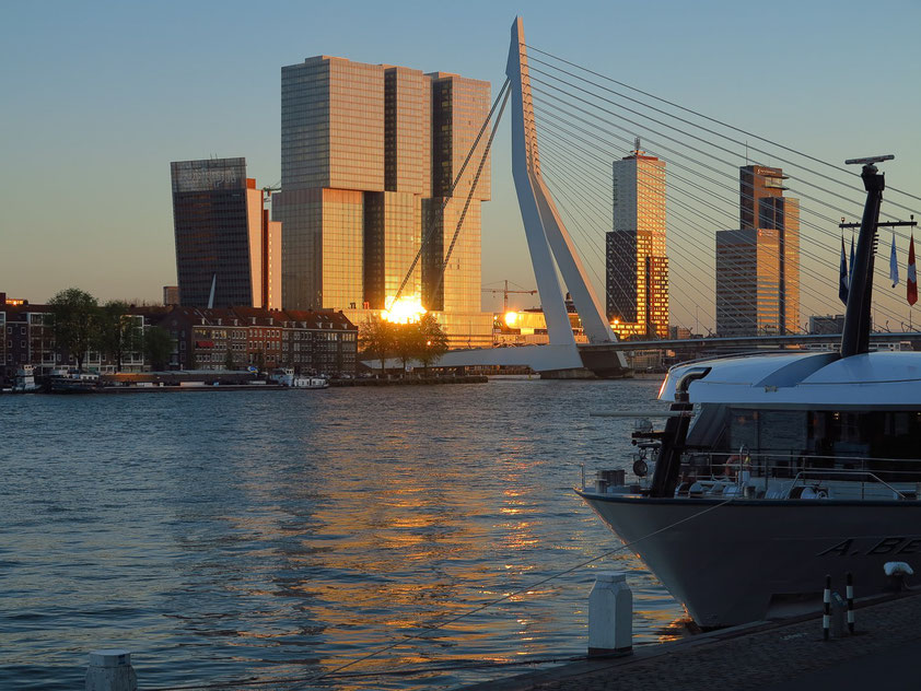 Die untergehende Sonne spiegelt sich im Hochhaus De Rotterdam. Blick vom nördlichen Ufer der Nieuwe Maas